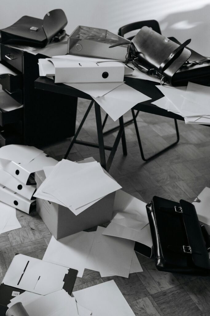 pexels-photo-6539020-6539020 A chaotic office desk covered with scattered papers, folders, and a briefcase.