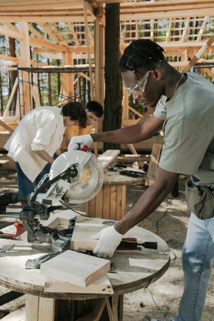 pexels-photo-8820181-8820181 Focused carpenter using a circular saw at an outdoor construction site, cutting wood precisely.